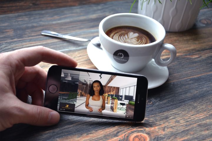 Woman Sitting on Sofa While Looking at Phone With Laptop on Lap