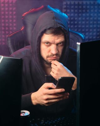 A man in a hoodie using a smartphone, representing cybersecurity themes.