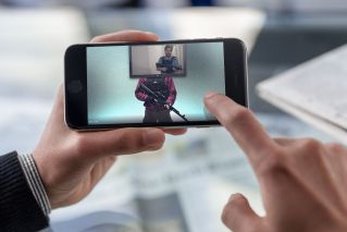 A cheerful man wearing a stylish outfit uses a smartphone while seated in a modern indoor setting.